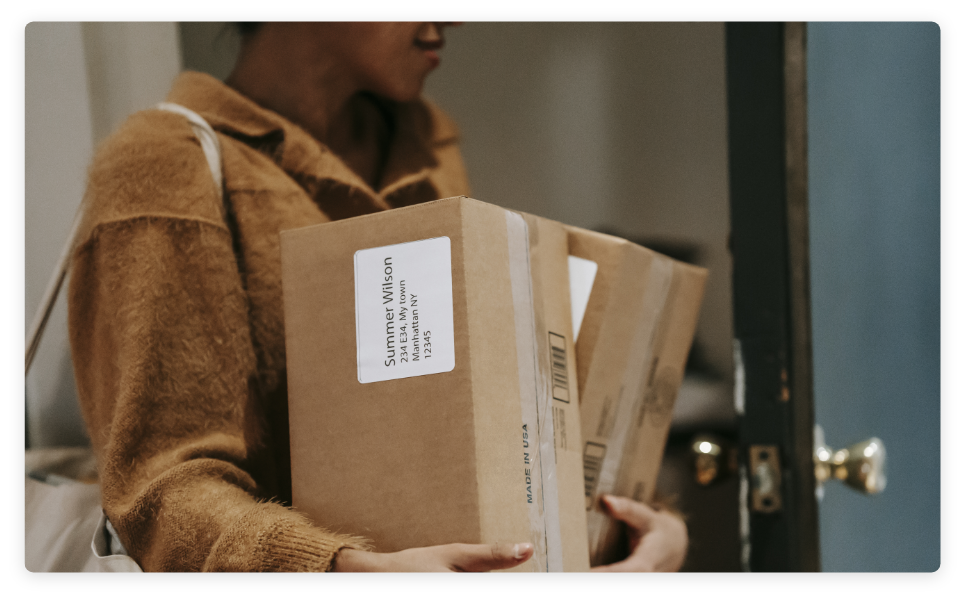 Individual holding an armful of delivery boxes while opening door to enter an office or home.